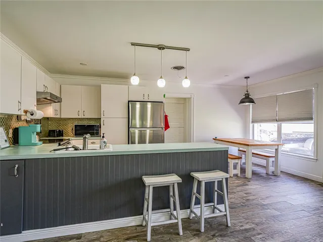 a kitchen with kitchen island granite countertop a table chairs sink and cabinets