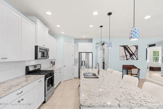 a large kitchen with stainless steel appliances kitchen island granite countertop a sink and a refrigerator