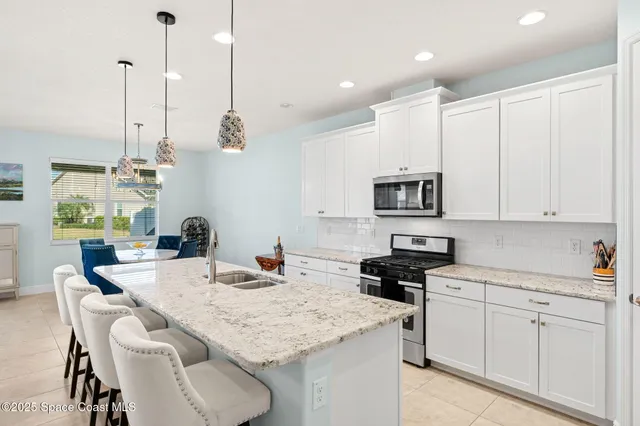 a kitchen with stainless steel appliances kitchen island granite countertop a sink a stove and a wooden floor