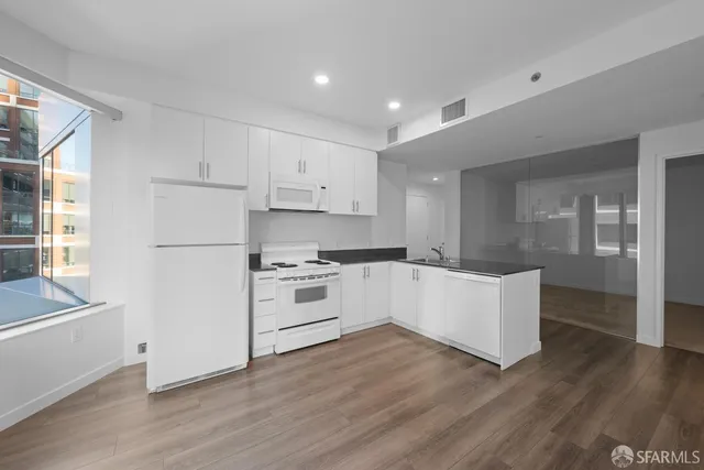 a kitchen with granite countertop a refrigerator stove top oven and sink