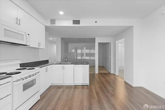 a living room with stainless steel appliances wooden floor and large window