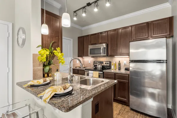 a kitchen with granite countertop a sink stainless steel appliances and cabinets