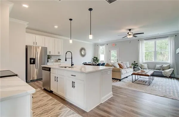 a living room with stainless steel appliances granite countertop furniture wooden floor and a chandelier