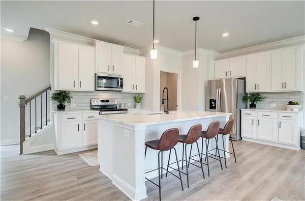 a kitchen with stainless steel appliances granite countertop a refrigerator a stove a microwave oven a sink dishwasher and a dining table with wooden floor