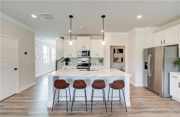 a kitchen with stainless steel appliances kitchen island granite countertop a refrigerator a stove a kitchen island with a dining table and chairs