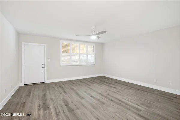 an empty room with wooden floor and windows