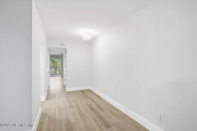 a view of a room with wooden floor and a white wall