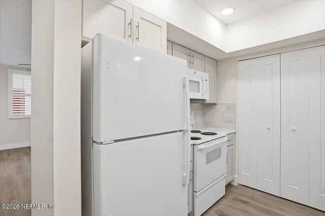 a white refrigerator freezer and a wooden floor