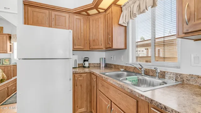 a kitchen with stainless steel appliances granite countertop a sink a refrigerator and a granite counter tops with a large window