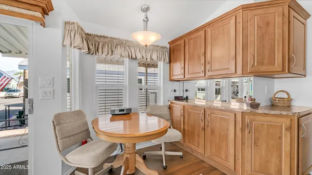 a kitchen with stainless steel appliances granite countertop a dining table chairs and a refrigerator