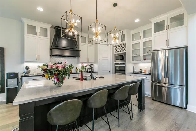 a kitchen with stainless steel appliances granite countertop a dining table chairs and wooden floor