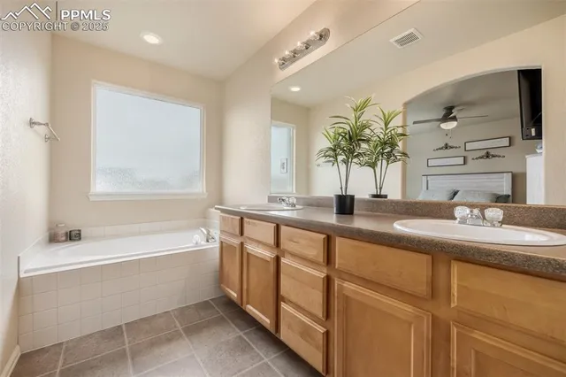 a bathroom with a granite countertop sink a large mirror a bathtub and window