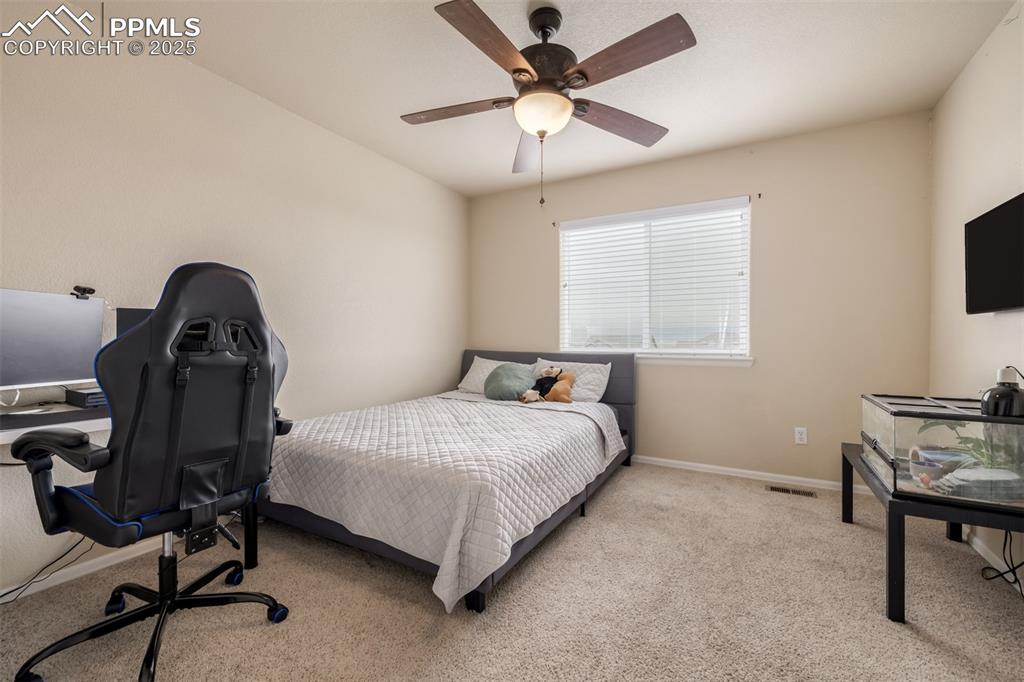 4966 Spokane Way Colorado Springs, CO 80911 - Photo 19 of 35 a bedroom with a bed a chair and a chandelier