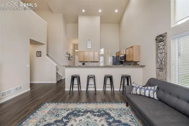 a living room with stainless steel appliances granite countertop furniture wooden floor and a rug