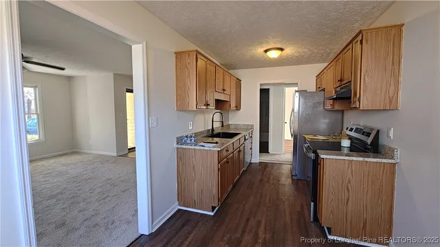 a kitchen with a refrigerator a stove top oven a sink dishwasher and wooden floor