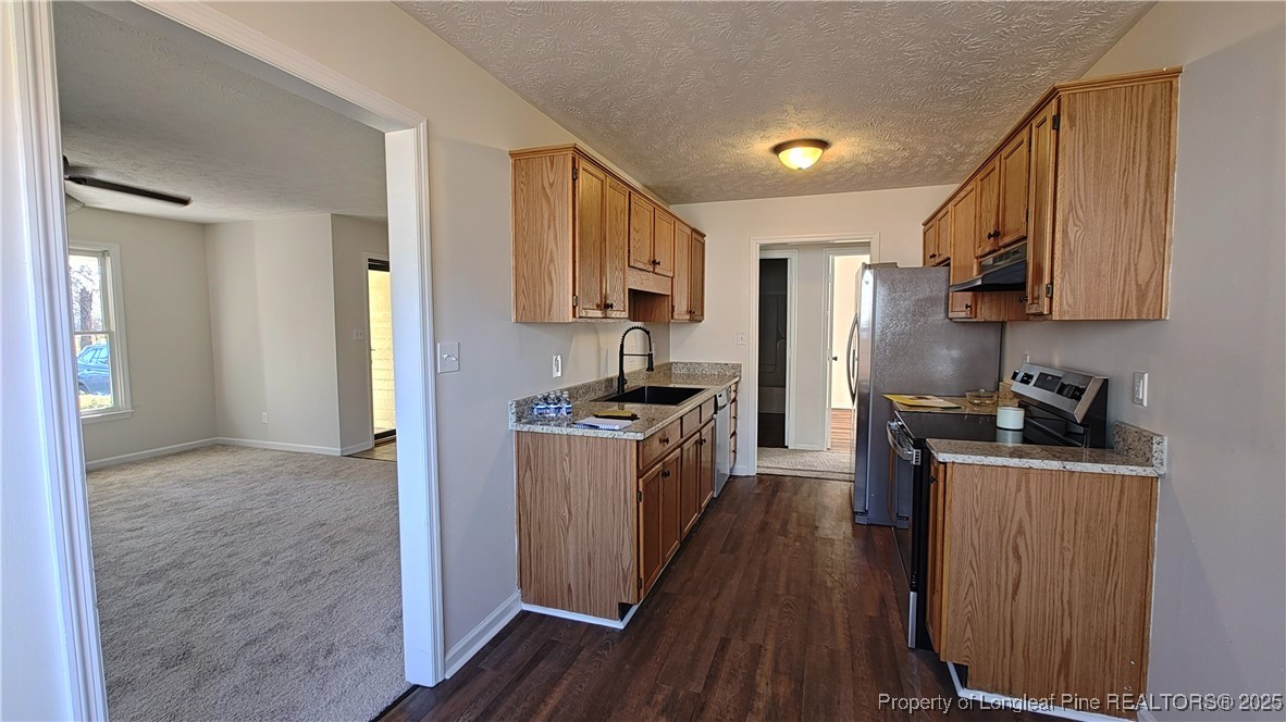 704 South Bethel Road Raeford, NC 28376 - Photo 6 of 32 a kitchen with a refrigerator a stove top oven a sink dishwasher and wooden floor