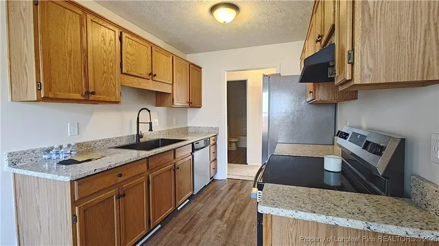 a kitchen with stainless steel appliances granite countertop a stove a sink dishwasher and cabinets with wooden floor