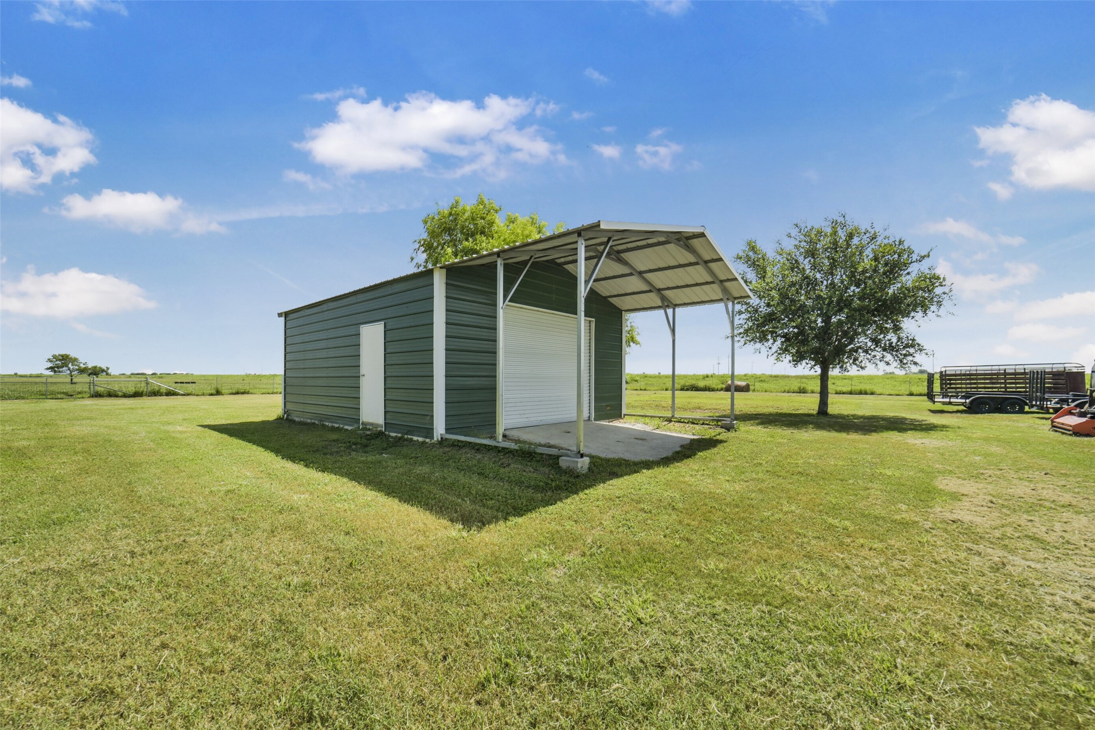 11301 South FM 441 Road El Campo, TX 77437 - Photo 33 of 43 20 x 20 metal storage shed with drive thru roll-up doors and an attached carport.