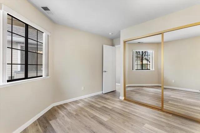 a view of empty room with wooden floor and fan