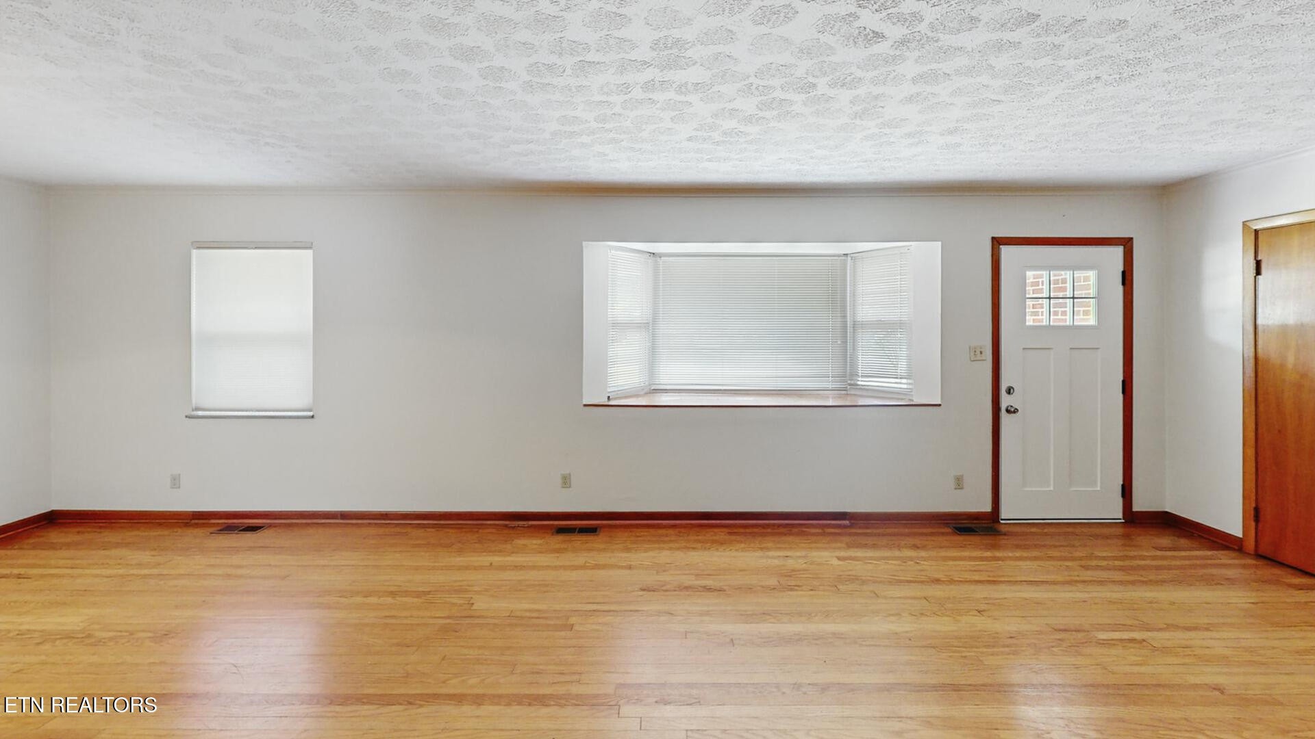 4004 Deerfield Road Knoxville, TN 37921 - Photo 2 of 34 an empty room with wooden floor and windows