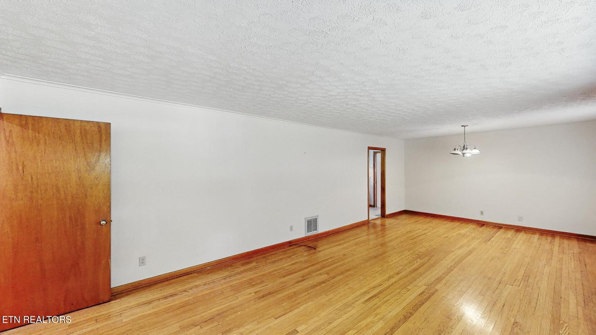 4004 Deerfield Road Knoxville, TN 37921 - Photo 3 of 34 an empty room with wooden floor and windows