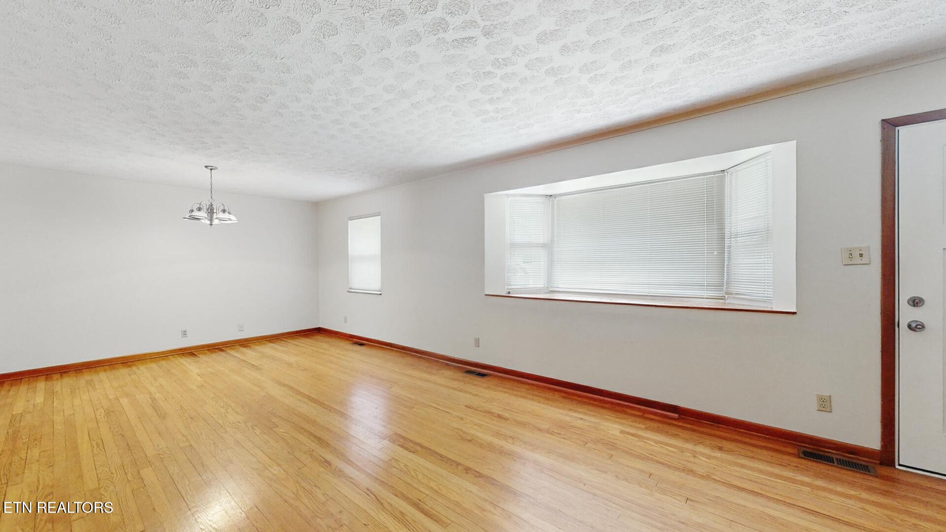 4004 Deerfield Road Knoxville, TN 37921 - Photo 5 of 34 a view of an empty room with wooden floor and a window