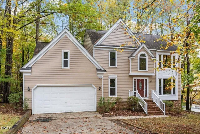 a view of a white house next to a yard with large tree