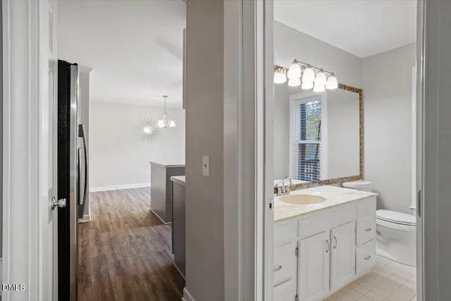 a room with kitchen island a sink a chandelier and wooden floor