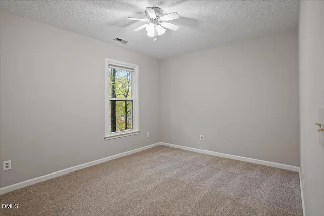 an empty room with a window and a fan