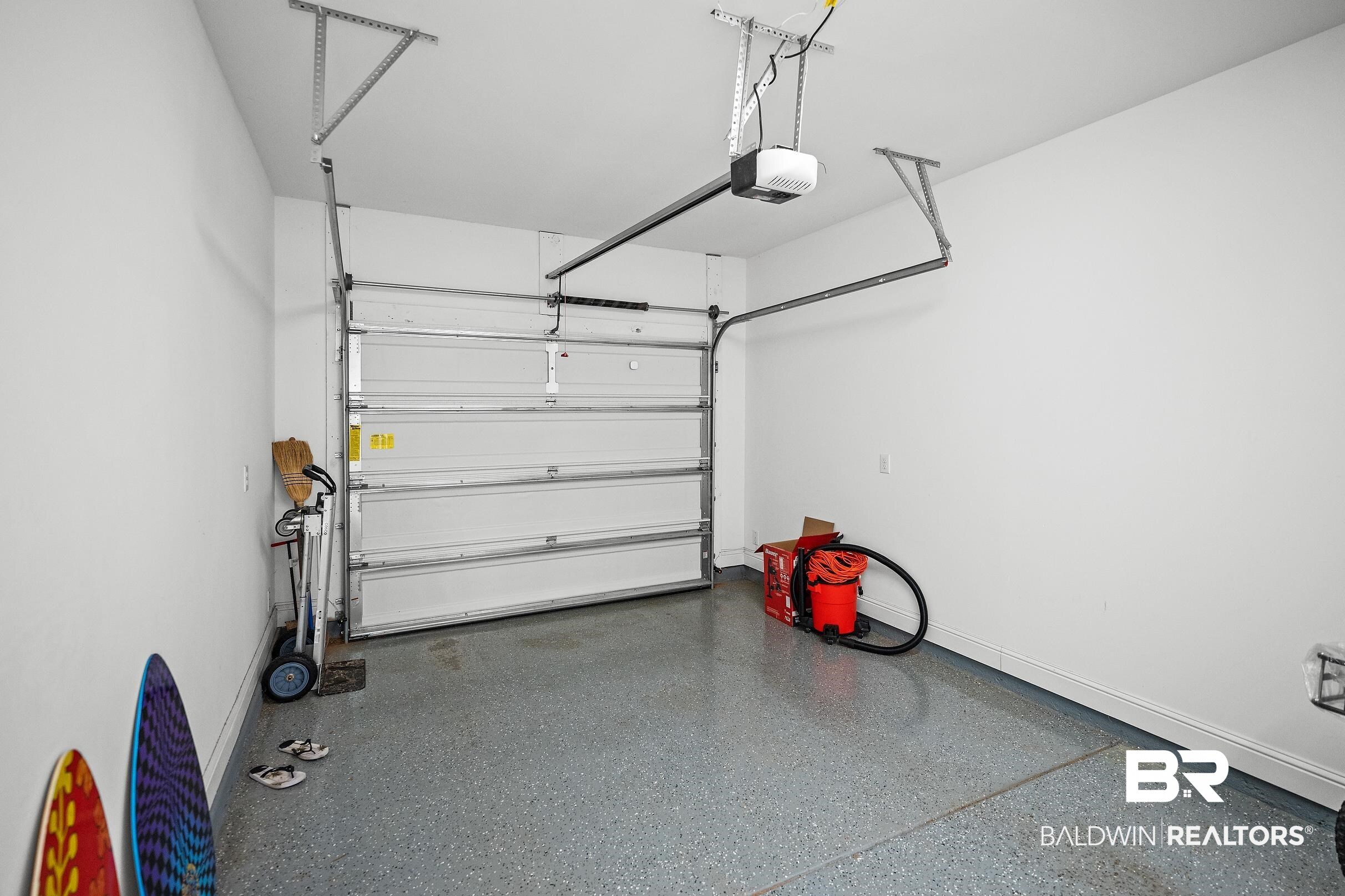 2651 South Juniper Street, Unit 2002 Foley, AL 36535 - Photo 20 of 23 Spacious garage featuring an automatic overhead door, a finished epoxy flooring, and ample vertical storage space