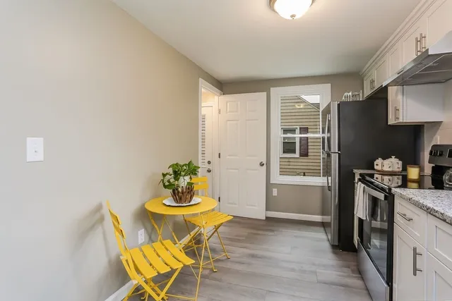 a kitchen with stainless steel appliances kitchen island granite countertop a refrigerator a stove a microwave oven with white cabinets and wooden floor