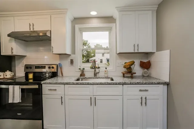 a kitchen with stainless steel appliances granite countertop a sink a stove and cabinets