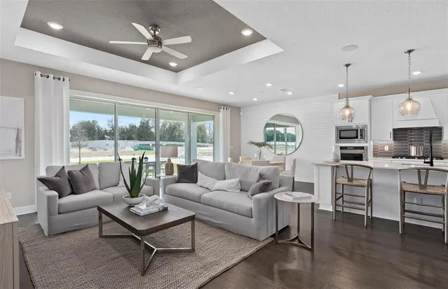 a living room with furniture kitchen view and a large window