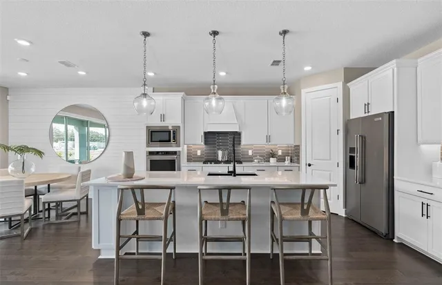 a kitchen with stainless steel appliances kitchen island granite countertop a table chairs and a refrigerator