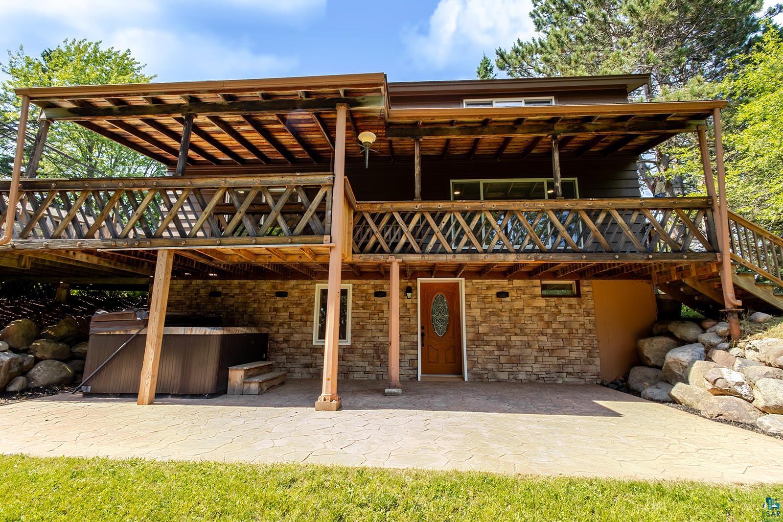 29 Ridge Road Esko, MN 55733 - Photo 35 of 41 Two-story exterior with a covered upper deck, lower stone-clad facade, and stamped concrete patio