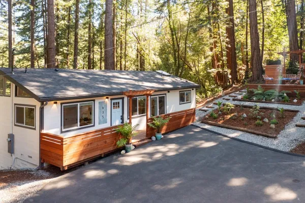 a view of a house with a yard chairs and wooden fence