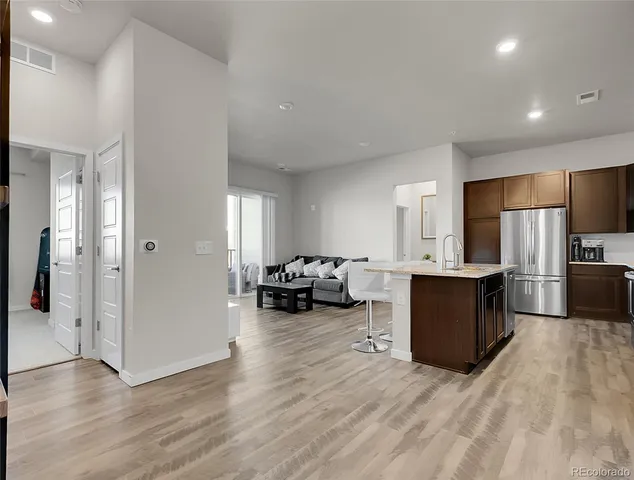 a view of living room kitchen with stainless steel appliances wooden floor and view living room