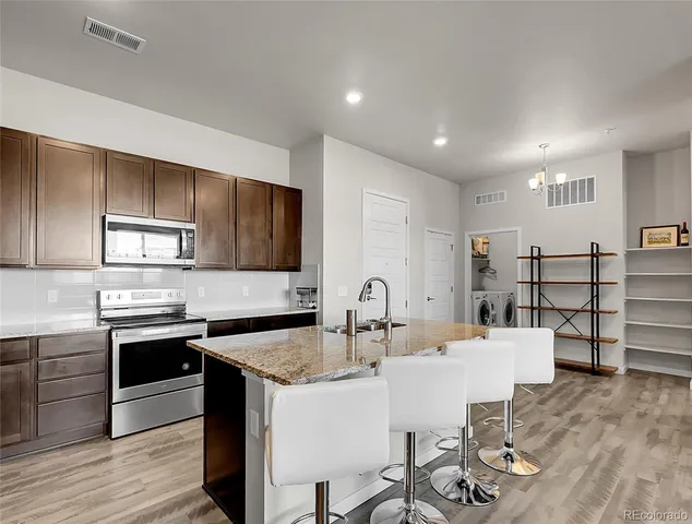 a kitchen with stainless steel appliances granite countertop a kitchen island a stove a table and chairs