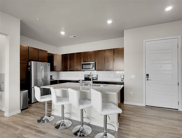 a kitchen with stainless steel appliances kitchen island granite countertop a refrigerator and a stove top oven