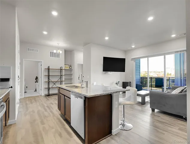 a living room with stainless steel appliances furniture and a flat screen tv
