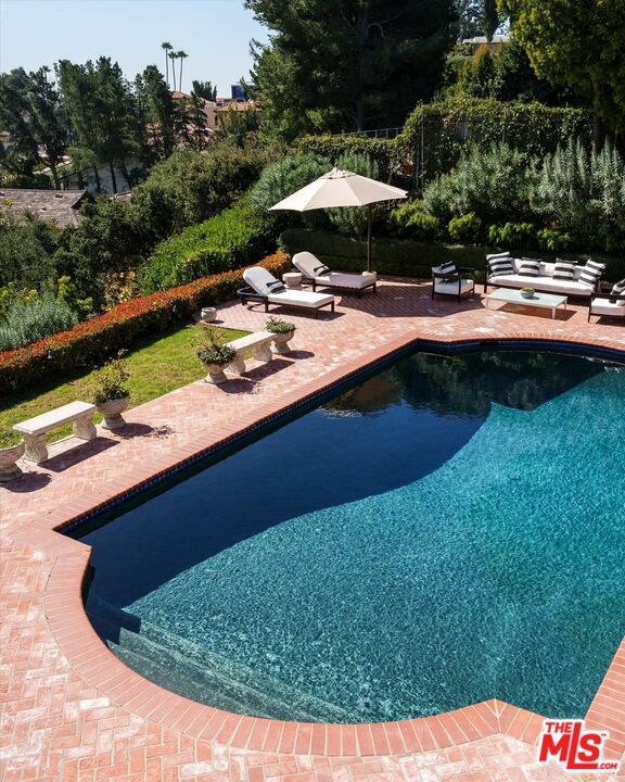 10814 Savona Road Los Angeles, CA 90077 - Photo 4 of 37 a view of swimming pool with lawn chairs under an umbrella