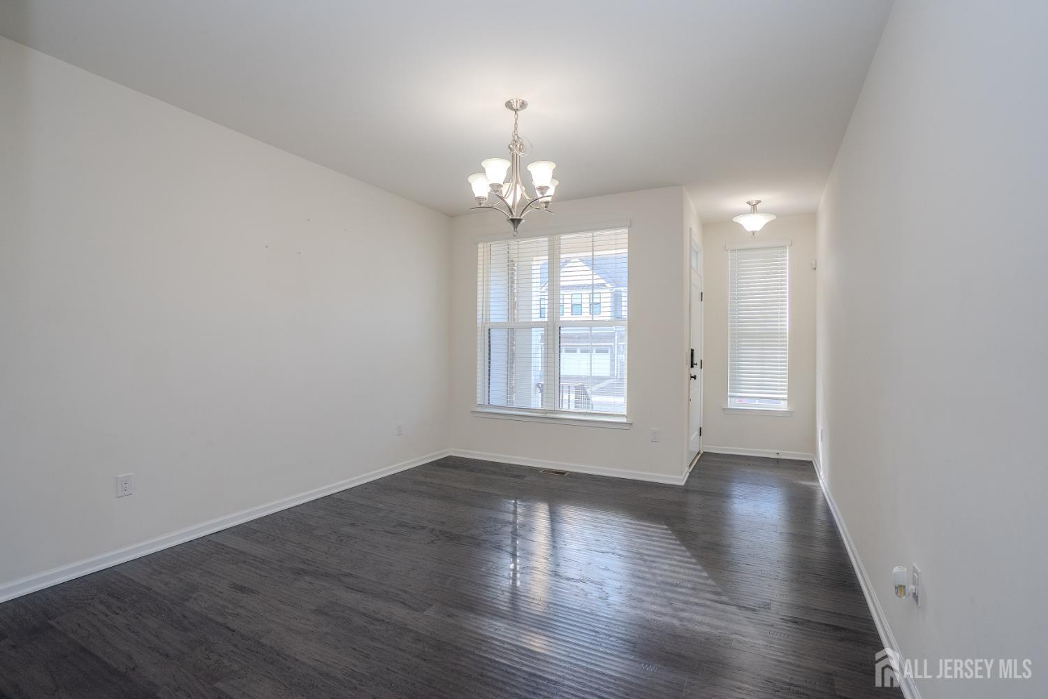 16 Clover Lane Monroe Township, NJ 08831 - Photo 3 of 36 an empty room with wooden floor chandelier and windows