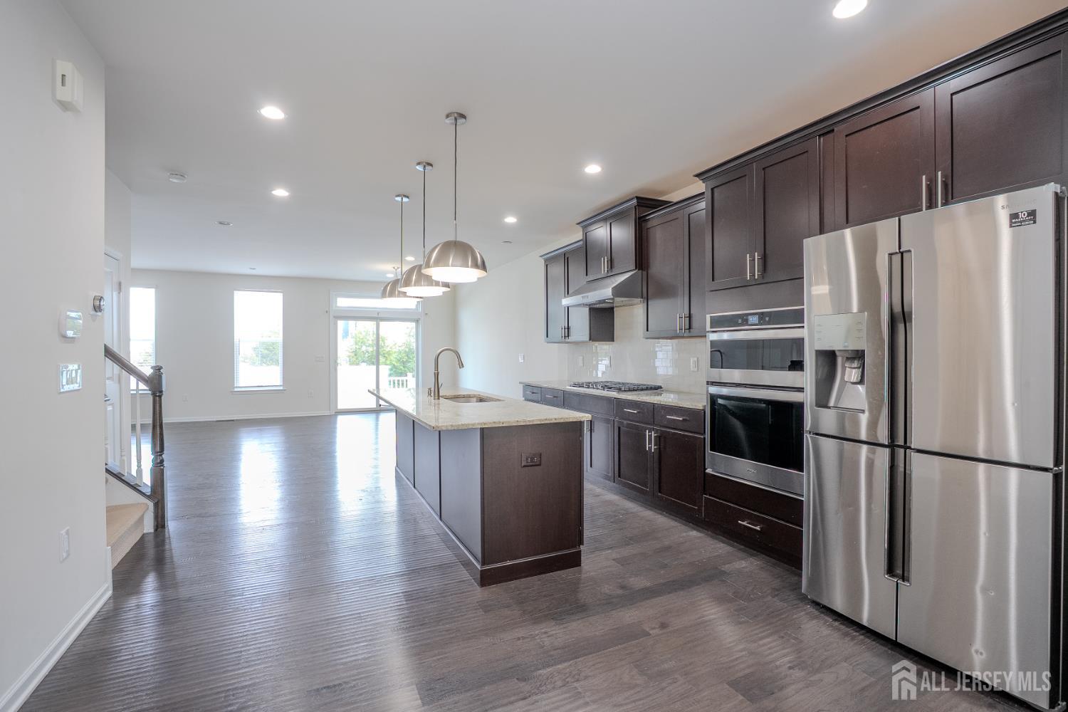 16 Clover Lane Monroe Township, NJ 08831 - Photo 5 of 36 a kitchen with kitchen island granite countertop a refrigerator a sink dishwasher a oven and a dining table with wooden floor