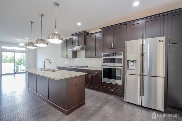 a kitchen with stainless steel appliances granite countertop a refrigerator a sink and a stove