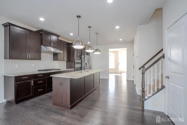 a large kitchen with stainless steel appliances kitchen island granite countertop a stove a sink dishwasher a microwave oven and a wooden cabinets