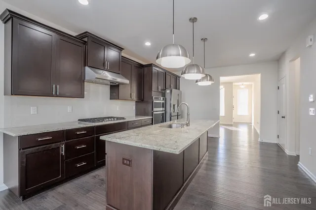 a kitchen with stainless steel appliances granite countertop a sink a stove and a wooden floors