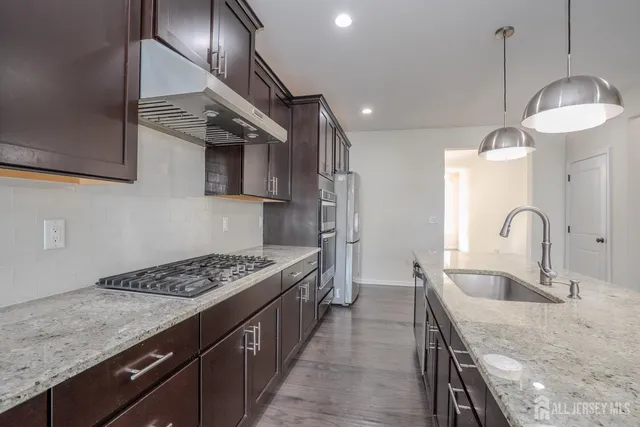 a kitchen with granite countertop a sink stainless steel appliances and cabinets