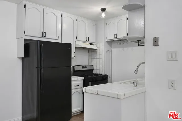 a view of a kitchen with refrigerator and cabinets