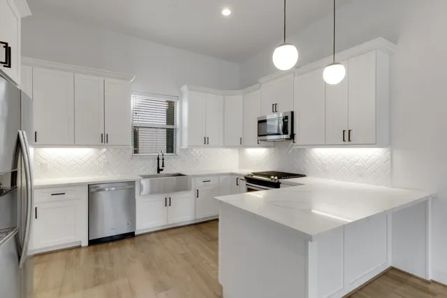 a large white kitchen with wooden floor and a sink