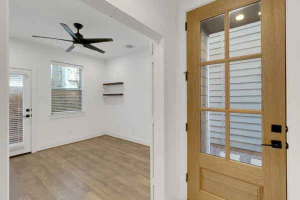 a view of empty room with wooden floor and fan